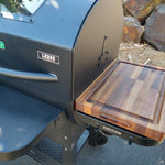 Outdoor grill with a wooden cutting board attached, featuring the brand 'Lodge'.