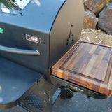 Outdoor grill with a wooden cutting board attached, featuring the brand 'Lodge'.