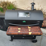 Black barbecue grill with wooden cutting board on a concrete surface