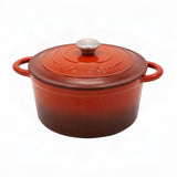 A red-orange enameled cast iron Dutch oven with a matching lid and silver knob, featuring side handles and the 'le creole' brand name embossed on the lid.