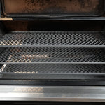 Open grill with two mesh racks inside, showing signs of use.