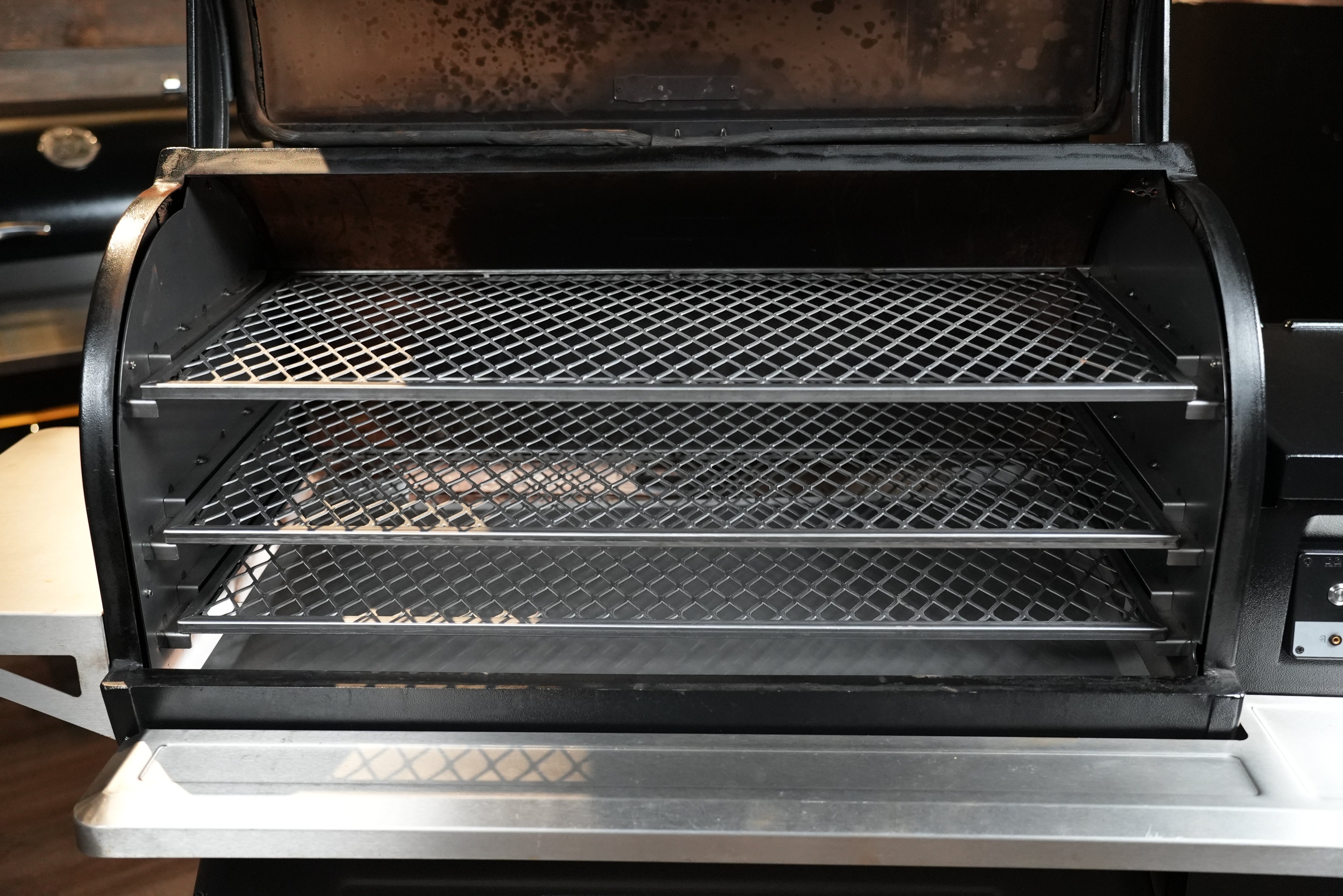 Open grill with two mesh racks inside, showing signs of use.