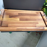 Wooden cutting board on a stand with a plant in the background