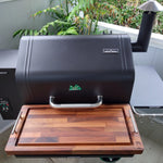 Black barbecue grill with a wooden cutting board on a patio