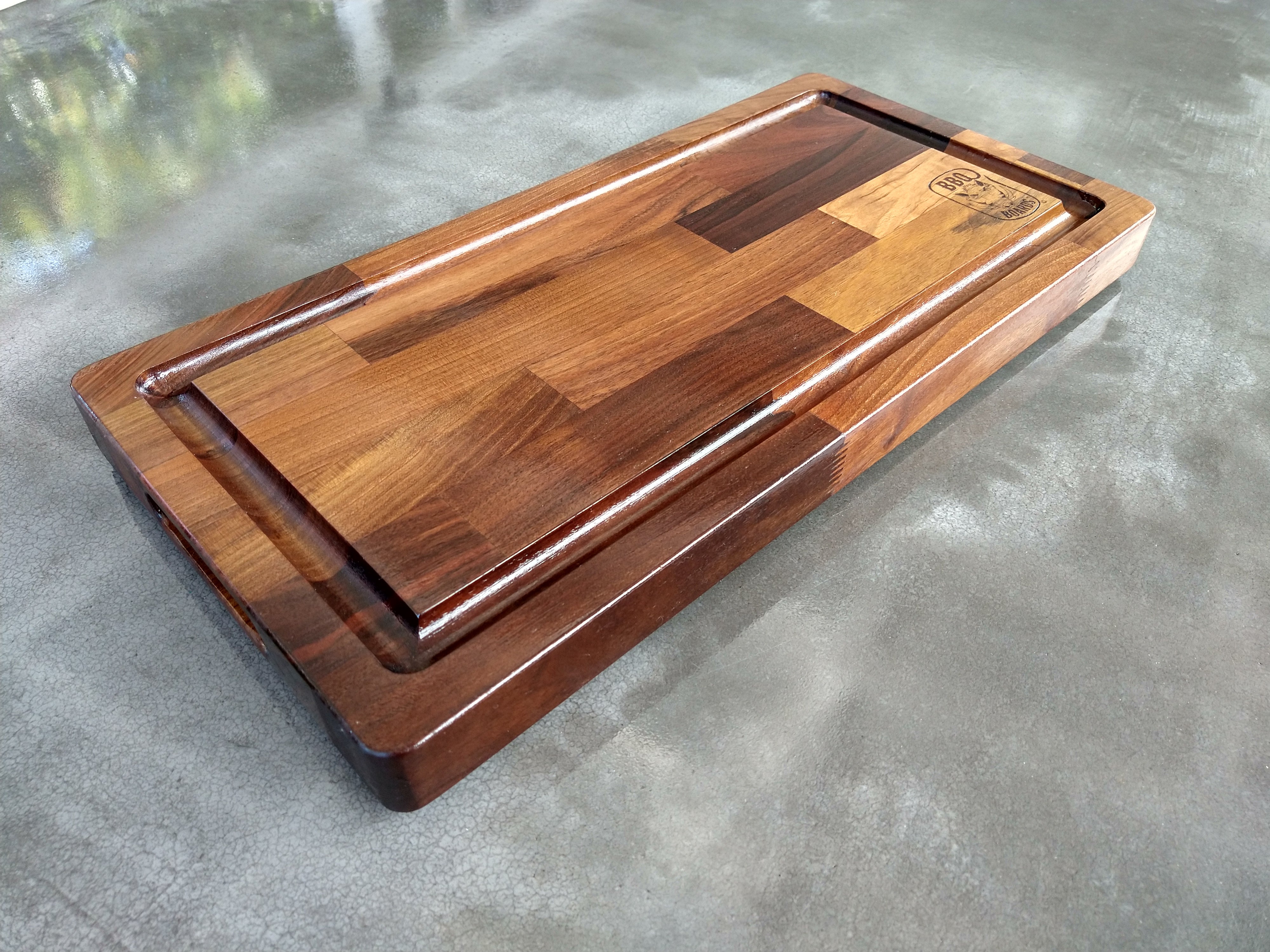Wooden cutting board with a logo on a concrete surface