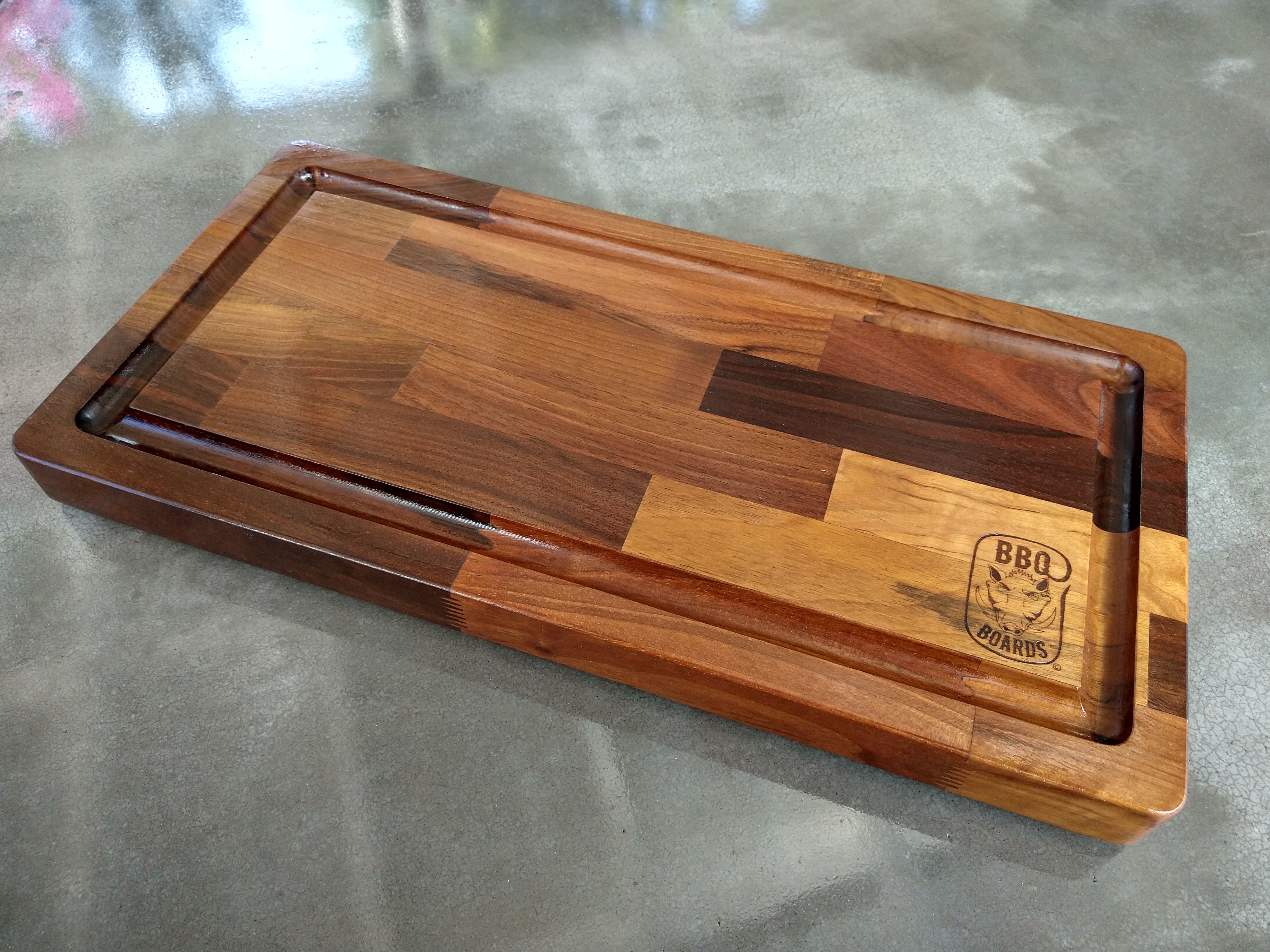 Wooden cutting board with a logo on a gray surface