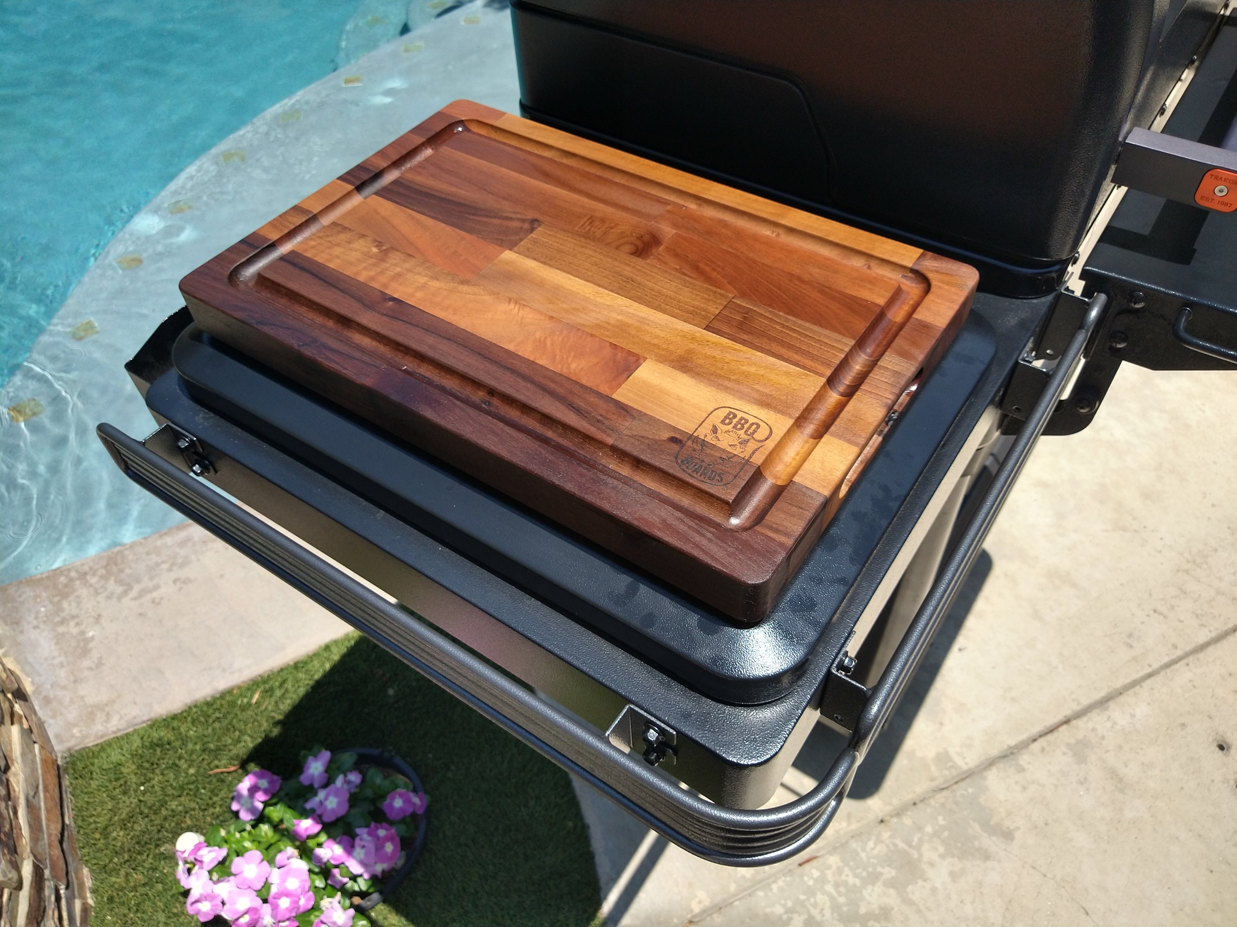 Wooden cutting board on a grill by a poolside