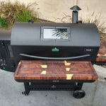 Black barbecue grill with wooden cutting board on a concrete surface
