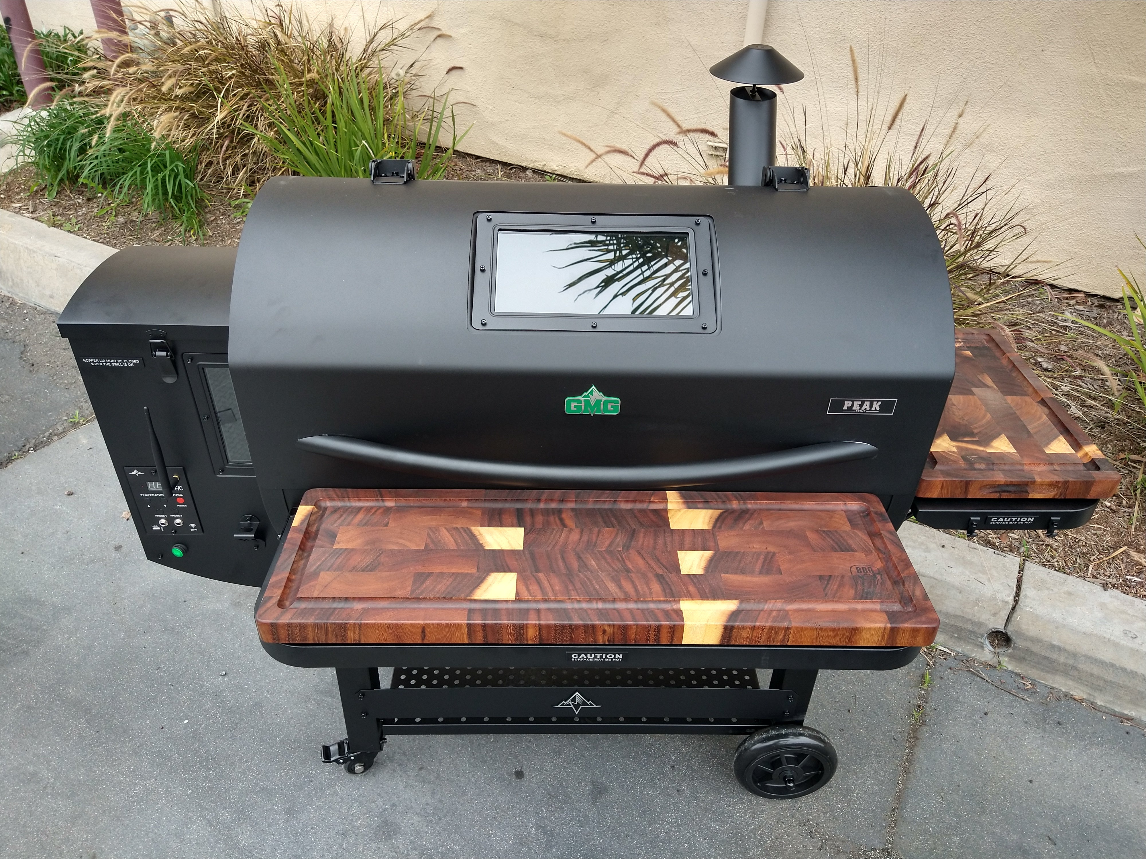 Black barbecue grill with wooden cutting board on a concrete surface